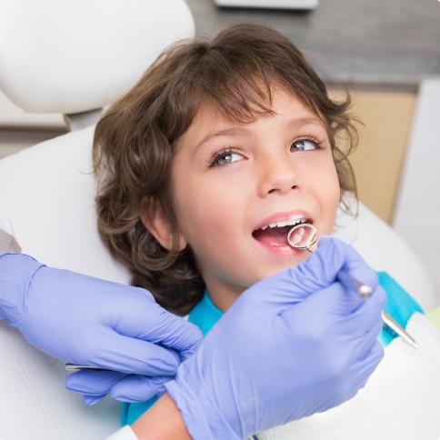Child smiling while dentist examines their teeth