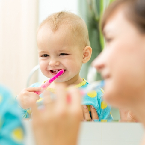 Parent helping their baby brush their teeth