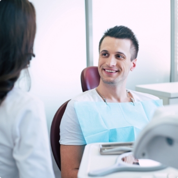 man in dental chair talking with dental team member