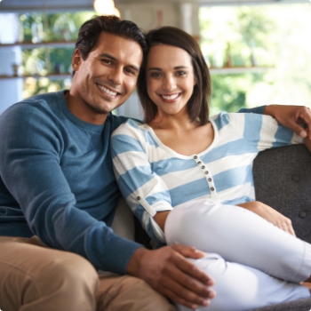 Smiling man and woman sitting on their couch