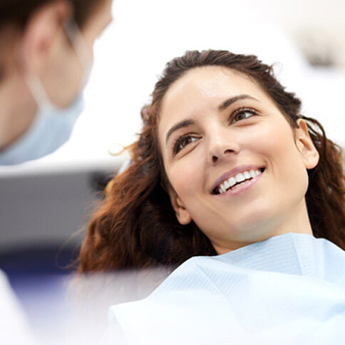 a smiling young woman looking at her dentist following direct bonding