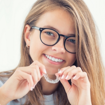 Teenage girl with glasses holding Invisalign