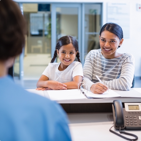 Mother and daughter talking to dental office receptionist