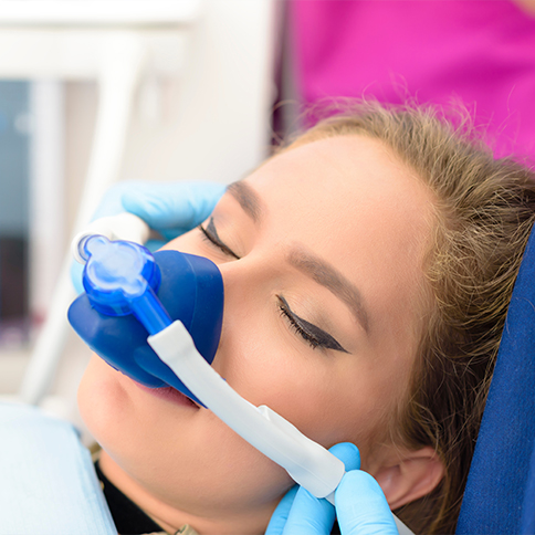 Woman wearing nitrous oxide sedation mask in dental chair