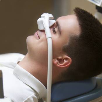 Man leaning back in dental chair with nitrous oxide mask on his nose