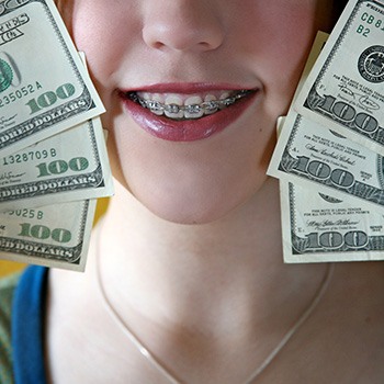 A smiling girl with braces holding hundred dollar bills next to her face