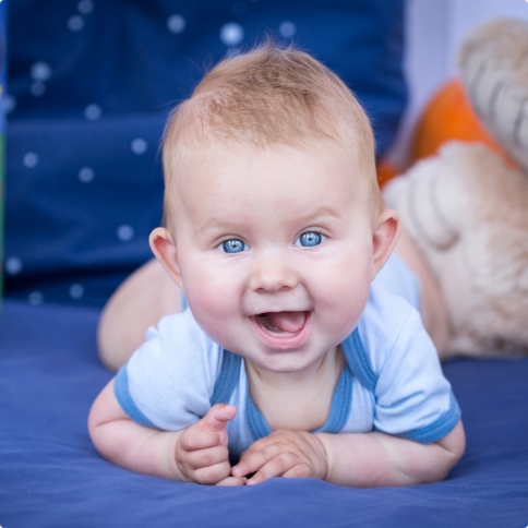 Baby laying on their stomach grinning wide