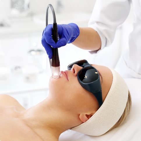 Dentist placing dental cold laser on chin of patient