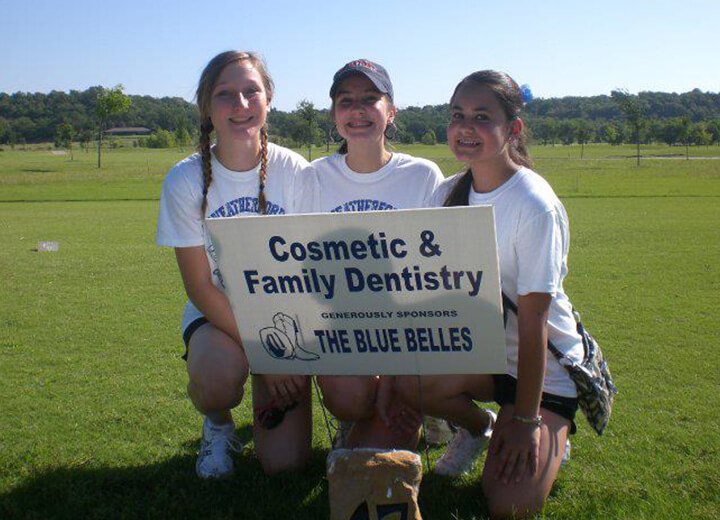 Three young girls with sign that reads Cosmetic and Family Dentistry generously sponsors the Blue Belles