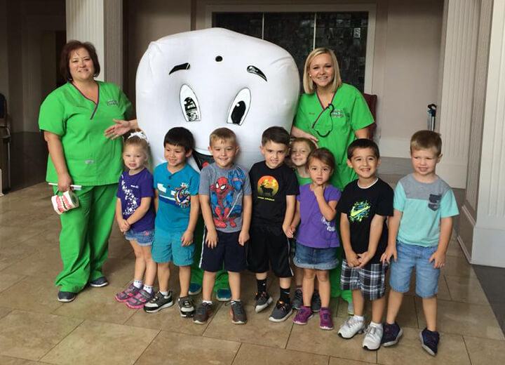 Dental team members and class of children with tooth mascot