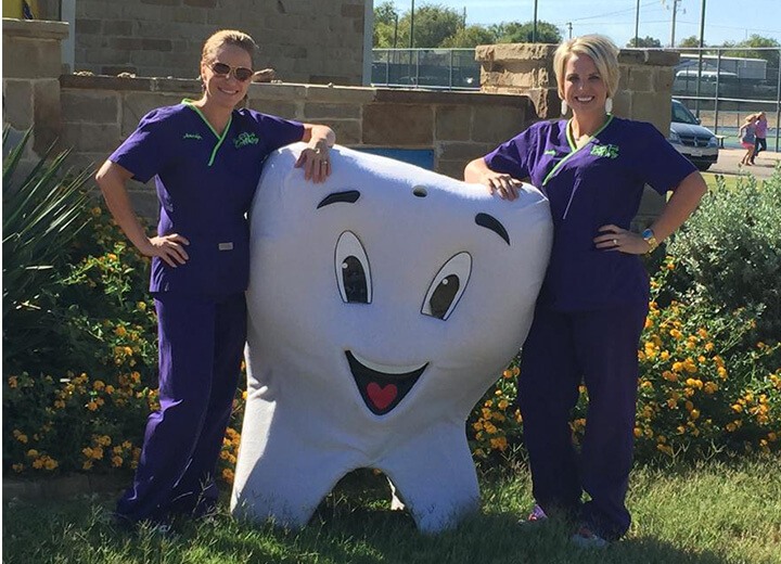 Two dental team members posting with tooth mascot