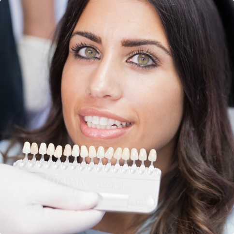 Dentist holding shade guide to a smiling patient