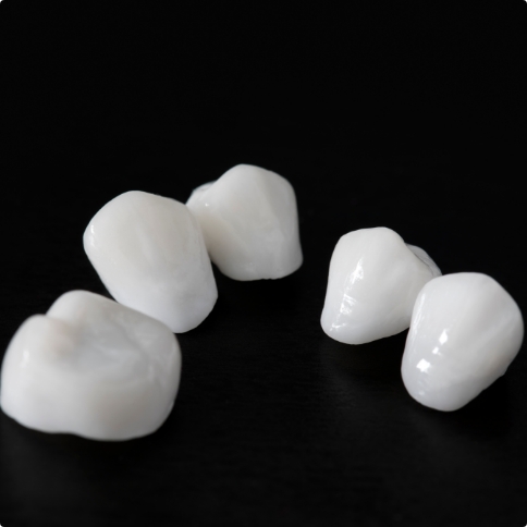 Five dental crowns against black background