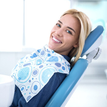 happy woman with attractive smile in dentists chair