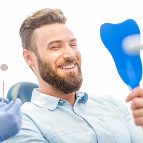 Dental patient admiring his smile in mirror
