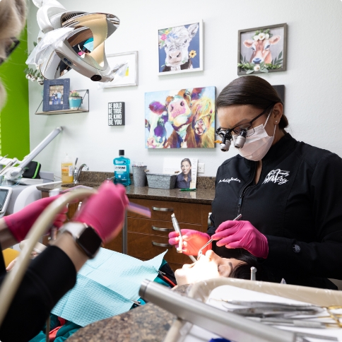Two dental team members performing a teeth cleaning on a patient