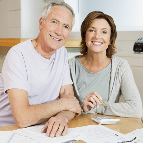 Older man and woman sitting at desk with papers and calculator