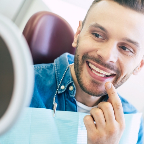 Dental patient pointing to his tooth while looking in mirror