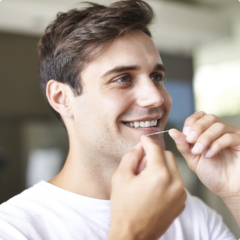 Man smiling while flossing his teeth