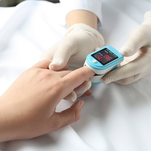 Dental team member placing pulse oximeter on finger of patient