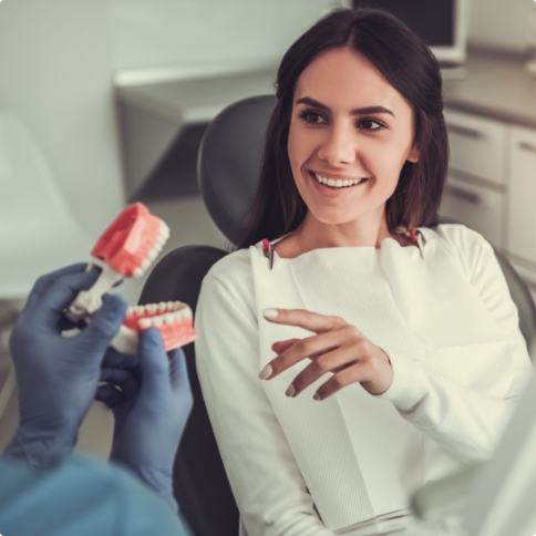 Dentist showing dentures in Weatherford to a woman in dental chair