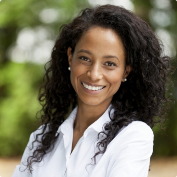 Woman in white button up shirt grinning outdoors