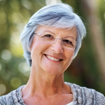 Senior woman with glasses smiling outdoors