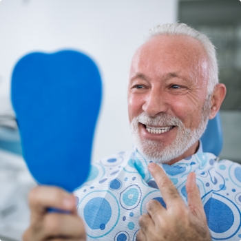 Dental patient admiring his smile in mirror