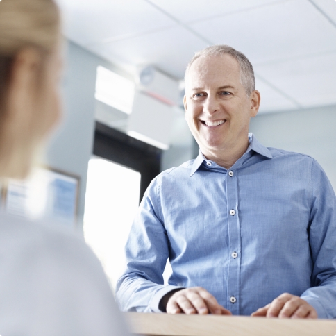 Man smiling at dental office receptionist