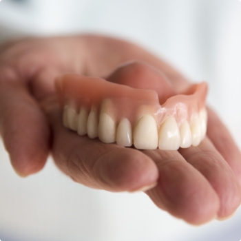 Hand holding a full upper denture