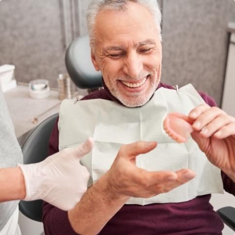 Senior man in dental chair holding a denture