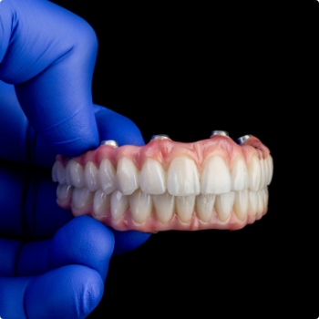Gloved hand holding an All on 4 denture