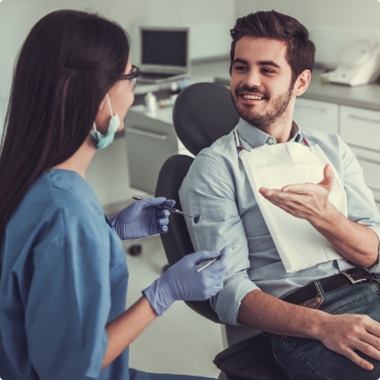 Man in dental chair talking to dental team member