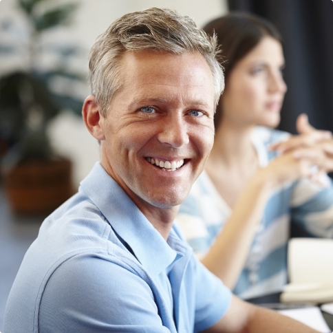 Smiling man in blue polo shirt sitting at table