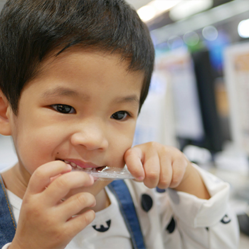 Child opening a plastic container with their teeth