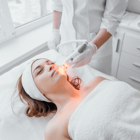 Dentist applying Fotona Lightwalker to the chin of a dental patient