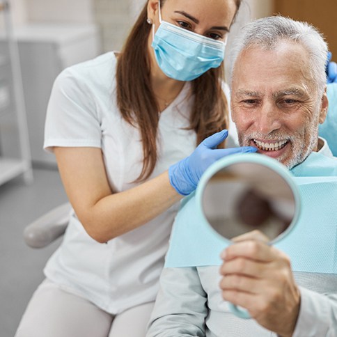 A man looking at his new dental implants with a dentist