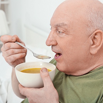 A man eating soup after dental implant surgery