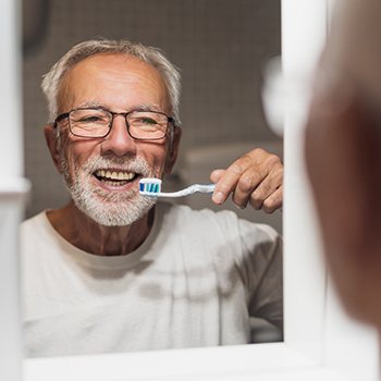 A man brushing his teeth after dental implant surgery