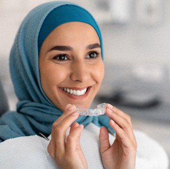 woman holding Invisalign at a dental appointment