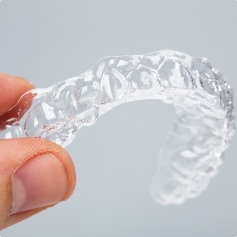 Hand holding an Invisalign clear aligner