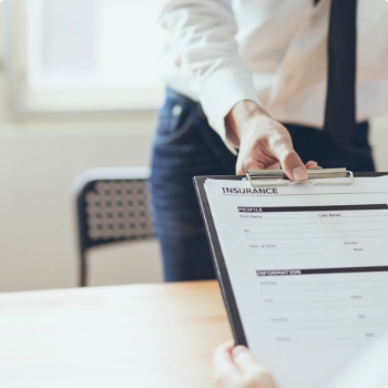 Person handing someone a clipboard with dental insurance forms