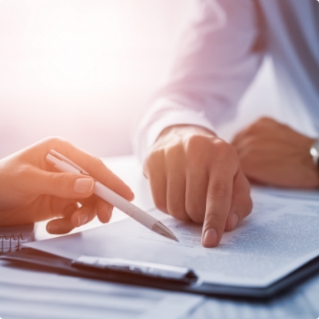 Man showing another person where to sign on clipboard