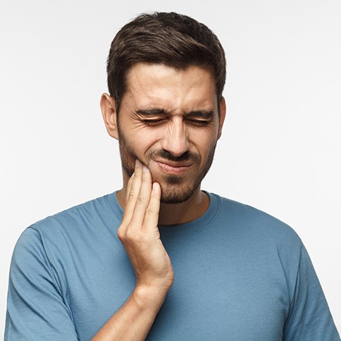 Frowning man holding the side of his face in pain