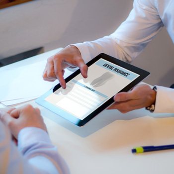 Two people zooming in on dental insurance on a digital tablet