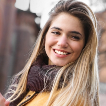 Blonde woman in scarf grinning outdoors