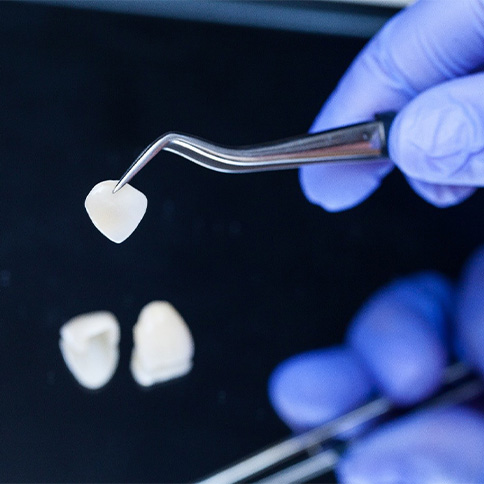 a pair of tweezers holding onto a dental veneer