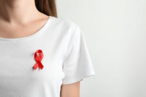 a woman wearing a white shirt with a red ribbon for oral cancer awareness
