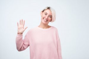 Smiling woman waves as recommended by her Weatherford dentist