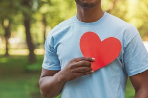 person holding a paper heart up to their chest